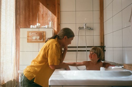parent gently helping toddler during bath time